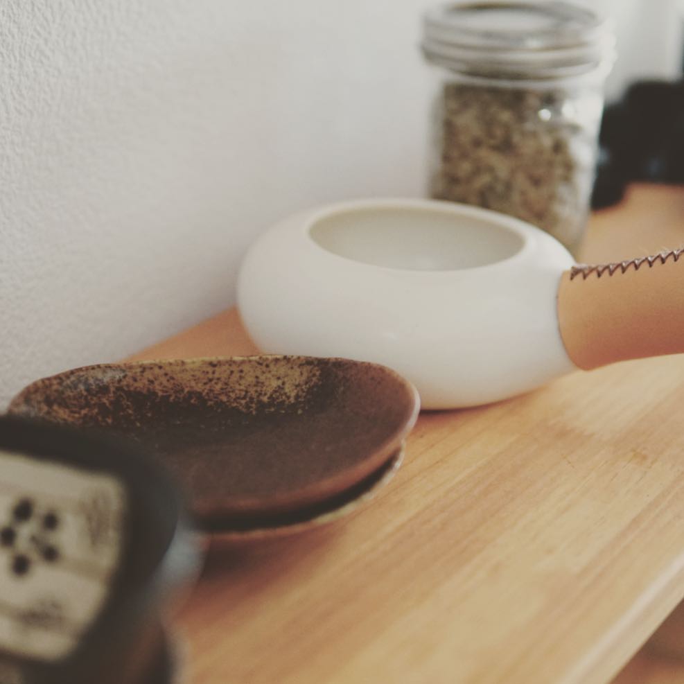 Zenroast with ceramic dishes and a jar of green coffee beans on a shelf
