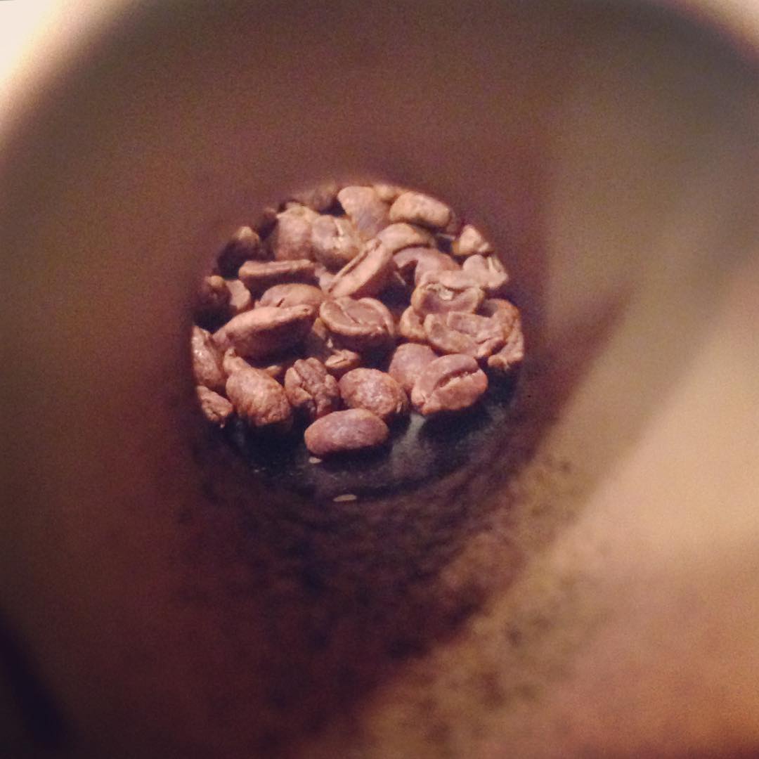 Roasted coffee beans seen through the hollow ceramic handle