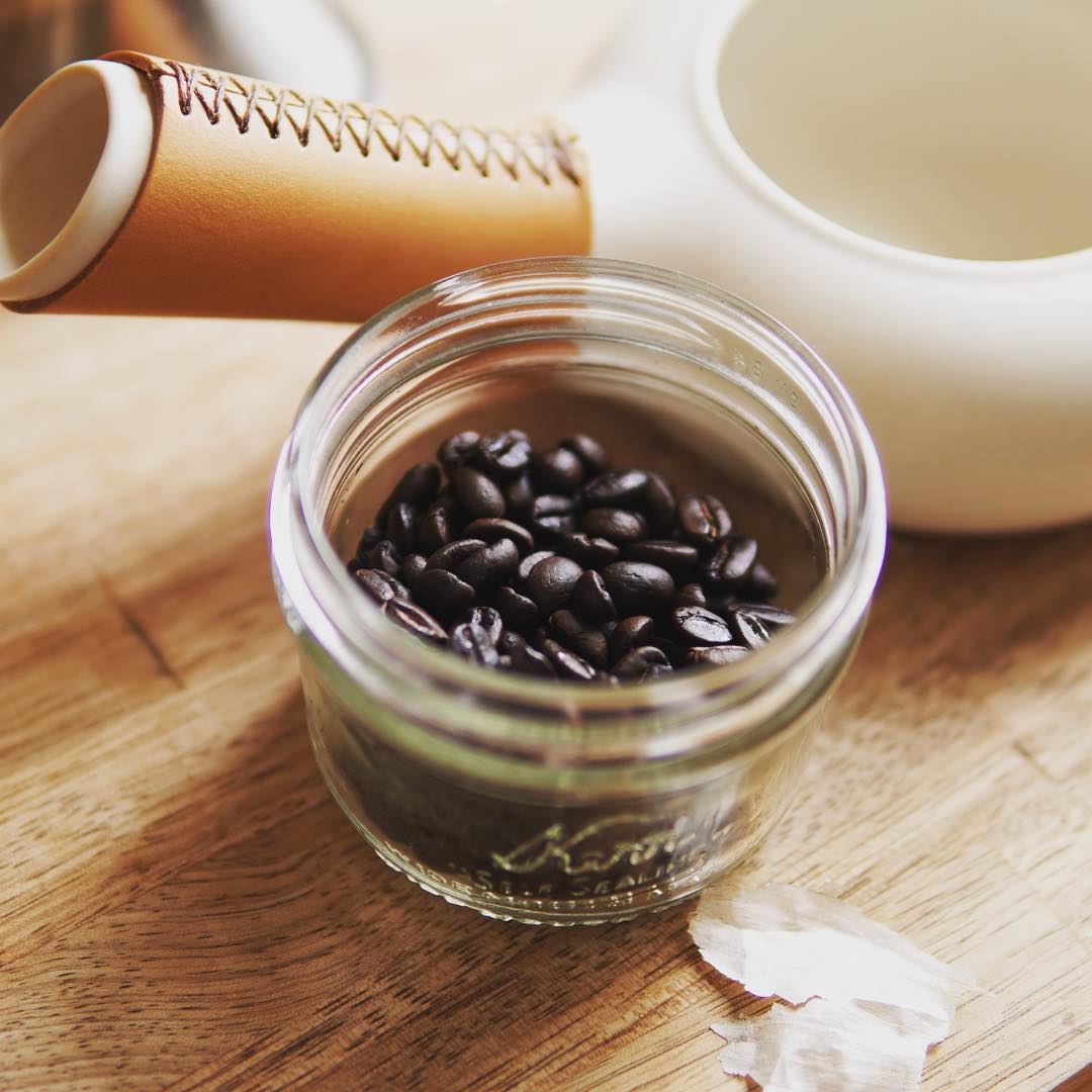 Freshly roasted coffee beans in a glass jar beside Zenroast